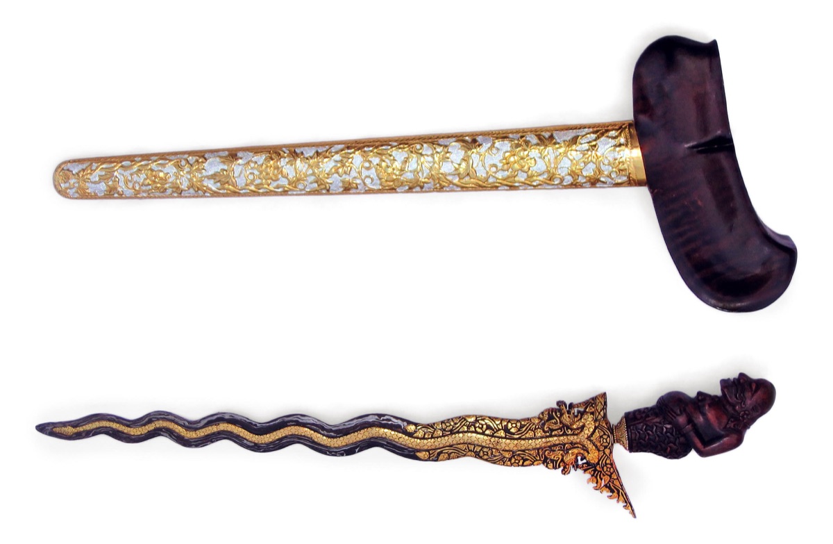 A kris with a carved handle and decorated sheath.